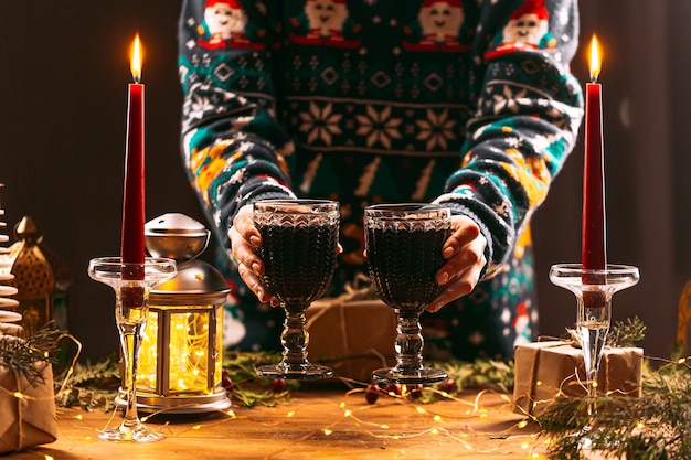 Femme dans un pull de Noël tenant des tasses de vin brillant o