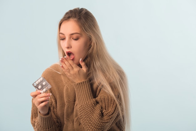 femme dans un pull avec des pilules dans les mains