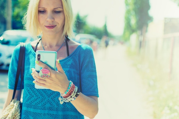 Femme dans la rue en regardant le téléphone portable en été