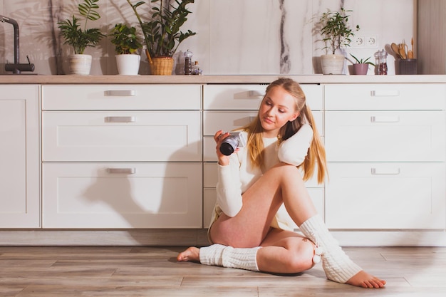 Une femme dans sa cuisine regarde des images sur l'appareil photo