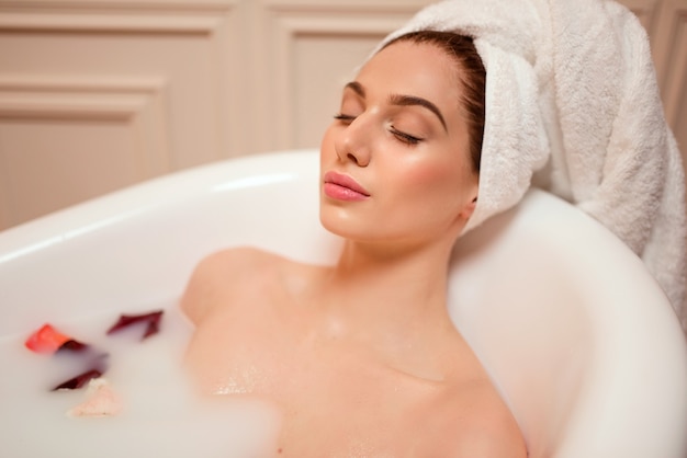 Femme dans la salle de bain avec des pétales de rose