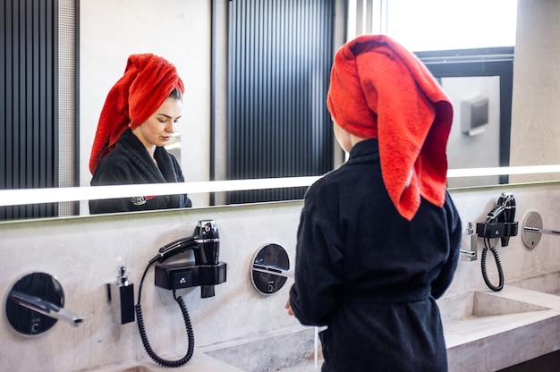 Femme dans la salle de bain séchant les cheveux