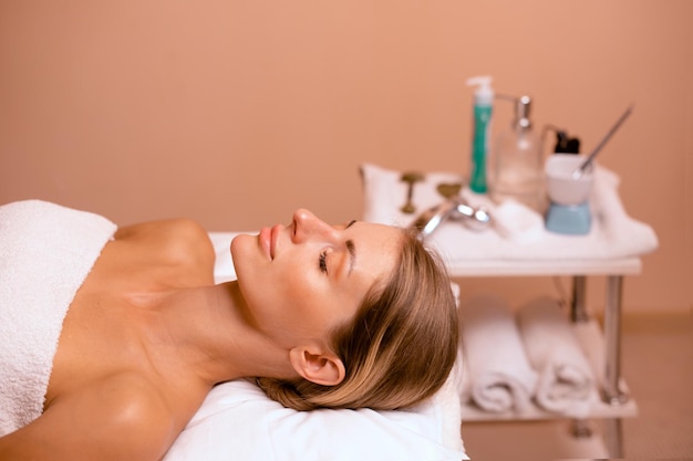 femme dans un salon de beauté prête à faire face à une procédure et à un massage sur fond beige avec espace de copie