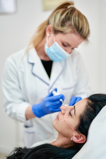 Femme dans un salon de beauté se faire des injections de botox sur la joue