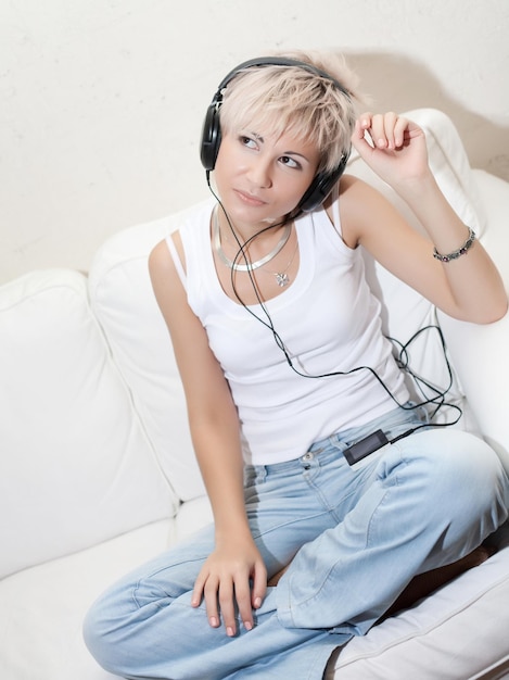 Femme dans le salon en écoutant un lecteur MP3 souriant