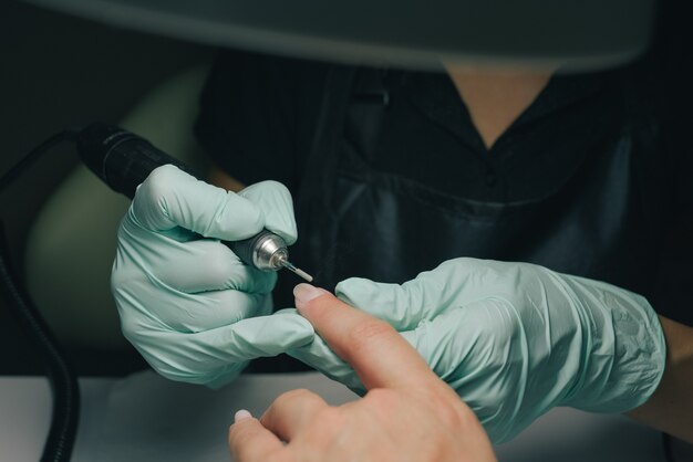 Femme dans un salon de manucure recevant une manucure par une esthéticienne. Concept de traitement de beauté. Processus de manucure