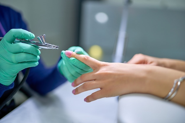 Femme dans un salon de manucure recevant une manucure de vernis gel par un maître manucure. Soin doux des ongles