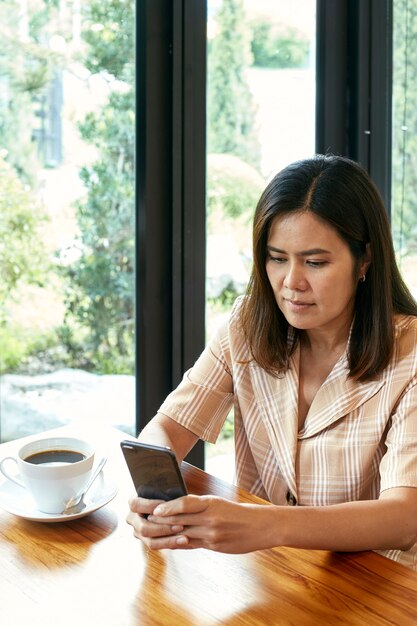 Femme dans le salon utilise un téléphone intelligent