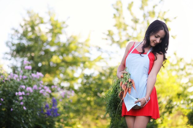 Une femme dans une serre cultive des légumes et des herbes Fille arrosant les tomates Se détendre dans le jardin Journée ensoleillée le week-end Fleurs dans la serre Sentir les fleurs dans la nature