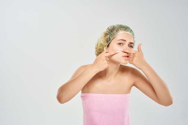 Femme dans une serviette rose squeeze les points noirs sur son visage problèmes de peau photo de haute qualité