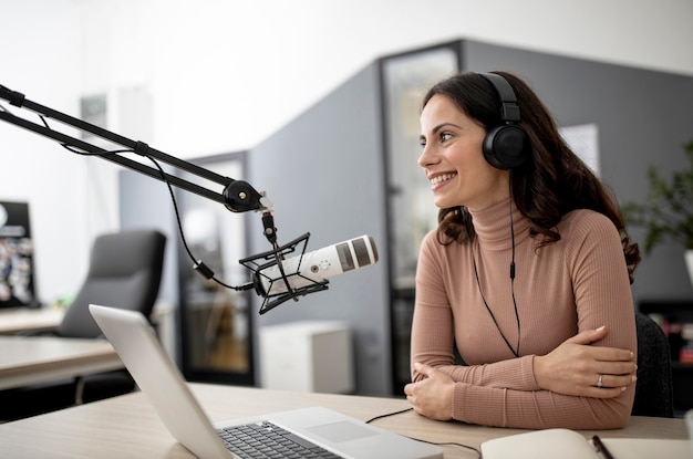 Photo femme dans un studio de radio avec microphone et ordinateur portable