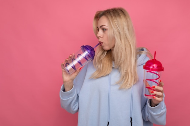 Une femme dans un sweat à capuche bleu à la mode tient deux verres à cocktail