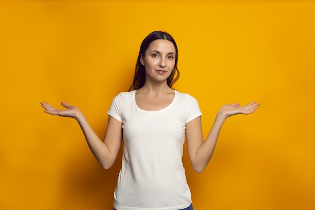 Femme dans un T-shirt blanc étend ses mains sur un mur jaune