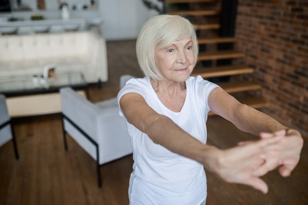 Femme dans un t-shirt blanc étirant ses bras vers l'avant