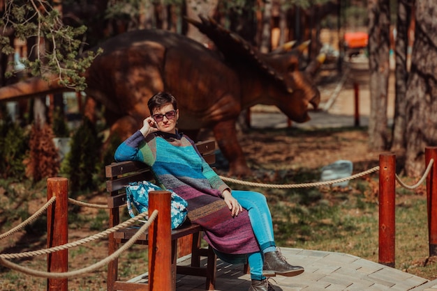 Une femme dans une tenue à la mode utilisant un smartphone tout en passant du temps dans le parc par une belle journée ensoleillée.