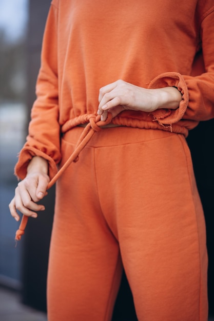 Photo femme dans une tenue de sport orange posant dans la rue