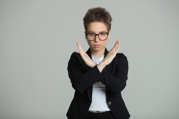 femme dans une veste noire avec une coupe courte sur un mur gris