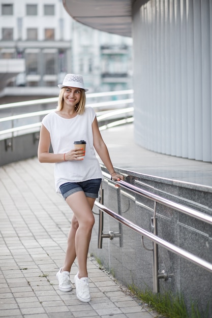 Femme dans la ville avec café, été et temps ensoleillé.