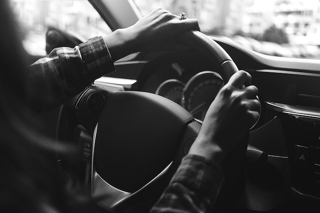 La femme dans la voiture conduit en noir et blanc.