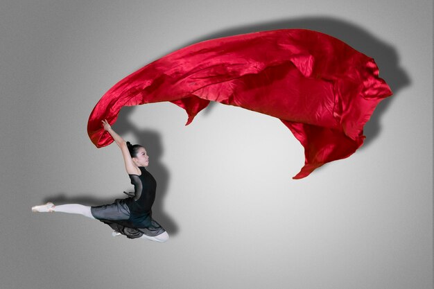 Photo une femme dansant en tenant un textile sur un fond gris.