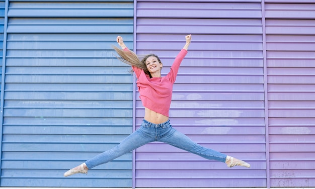 Femme danseuse sautant devant un mur coloré