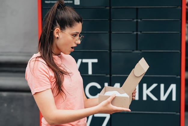 Une femme déballe un colis en carton avec une commande Internet en ligne