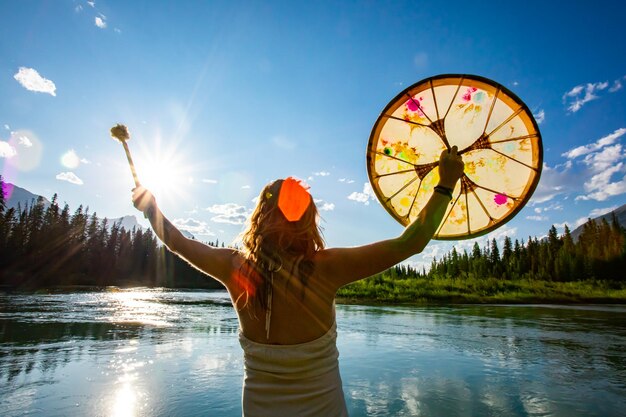 Photo une femme debout au bord d'un lac contre le ciel au coucher du soleil.