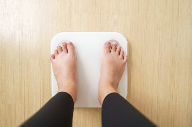 Femme debout sur des balances électroniques pour vérifier le poids. concept de régime alimentaire pour réduire le ventre