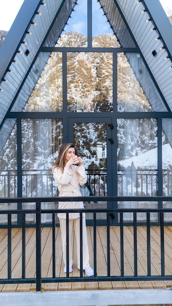 Photo une femme debout sur le balcon d'une cabane de cadre dans le parc d'hiver