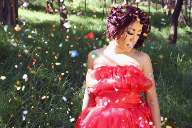 Photo une femme debout sur un champ herbeux avec des confettis qui tombent dans la forêt.