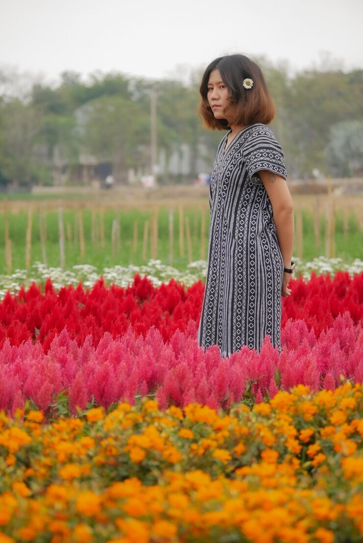 Photo une femme debout sur le champ près des plantes à fleurs rouges