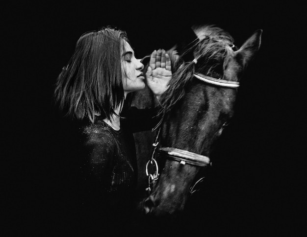 Photo une femme debout avec un cheval sur un fond noir