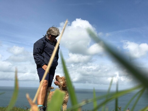 Photo une femme debout avec un chien au bord de la mer contre un ciel nuageux