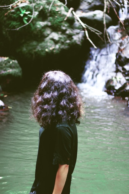 Photo une femme debout contre une cascade.