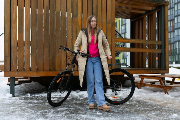 Photo femme debout à côté du vélo dans la neige