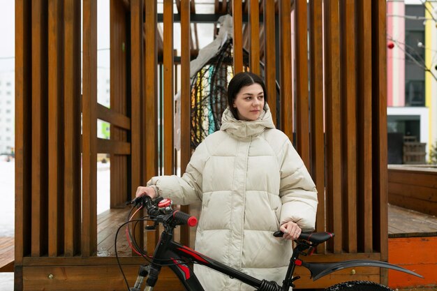 Femme debout à côté du vélo devant une structure en bois