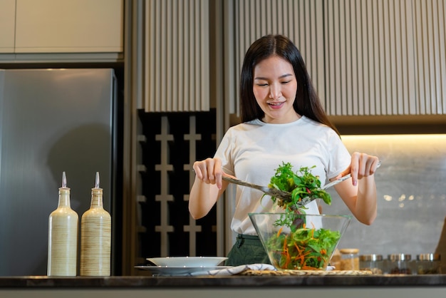 femme debout à la cuisine et faisant un bol de salade verte