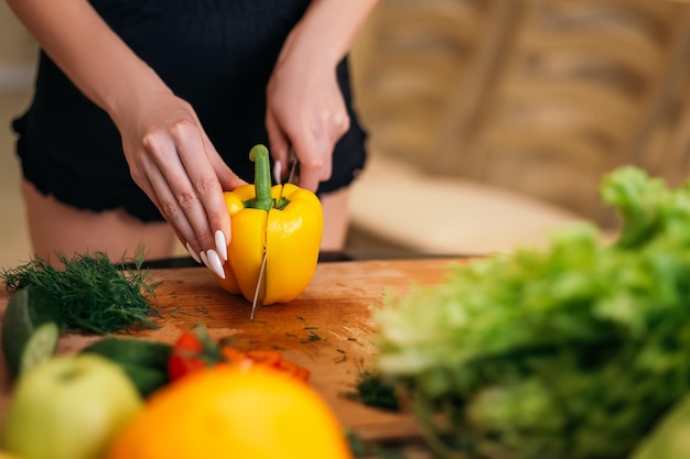 Femme debout dans la cuisine et hacher la salade avec des aliments sains