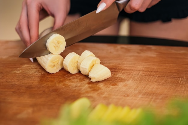 Femme debout dans la cuisine et hacher la salade avec des aliments sains