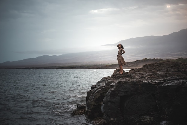 Femme debout dans une falaise avec l'océan ci-dessous