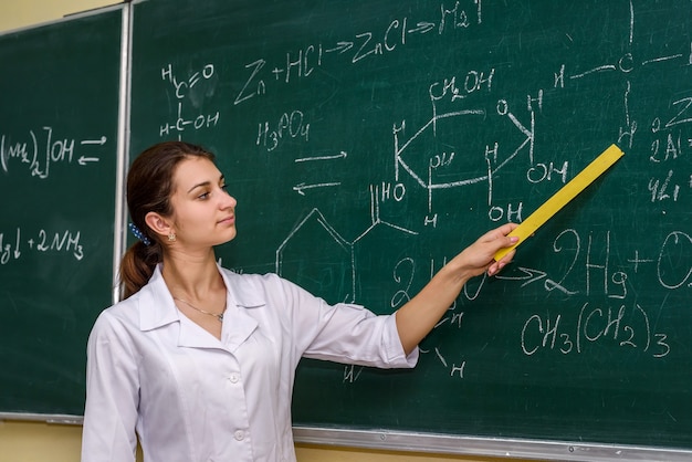 Femme debout dans la salle de classe de chimiste près du conseil et pointant dessus