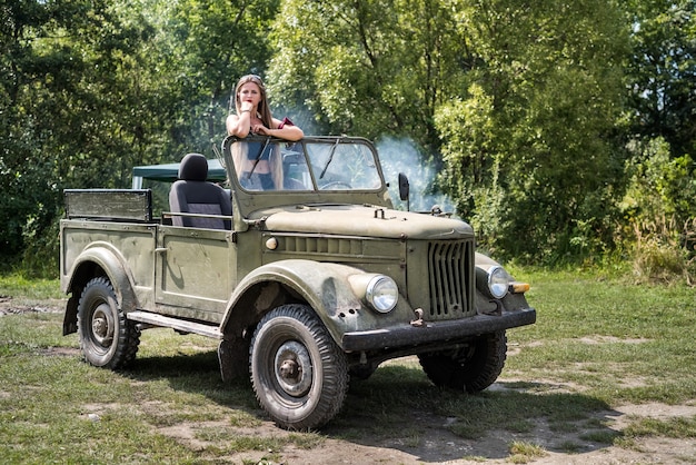 Femme debout dans une voiture militaire posant à l'extérieur