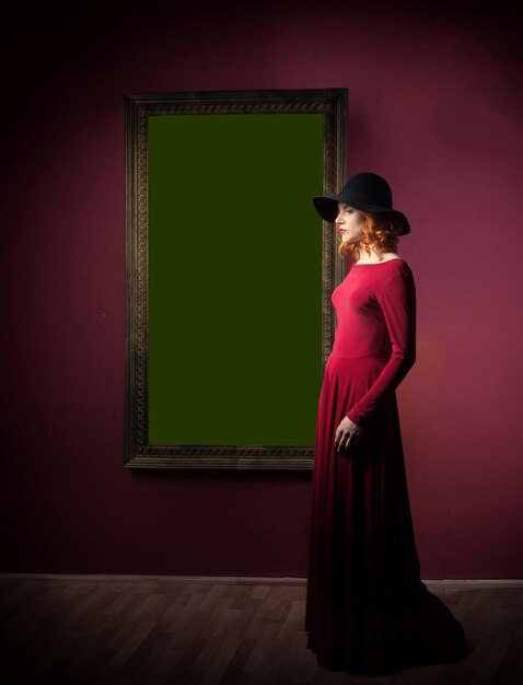 Femme debout devant l'antique portrait féminin accroché à un mur