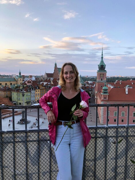 Photo femme debout devant les toits de la ville de varsovie avec vue sur la place du château tourisme en pologne au coucher du soleil