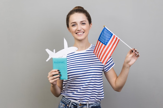 Femme debout avec drapeau américain et passeport avec avion en papier voyage à l'étranger