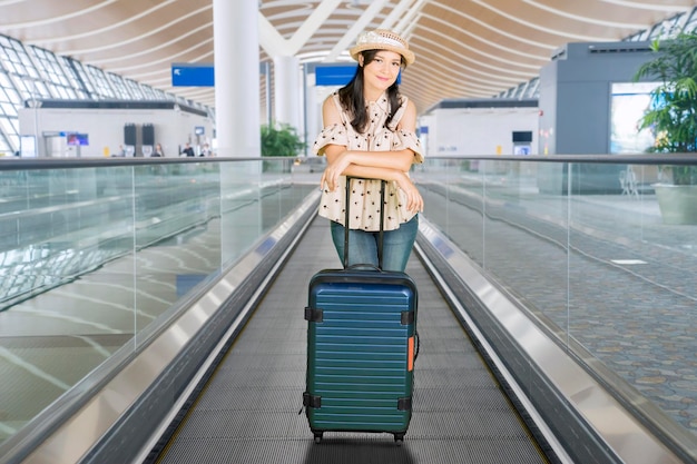 Femme debout sur l'escalator avec valise