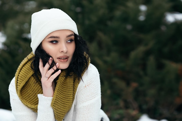 Femme debout à l'extérieur de la rue dans la forêt de neige hiver météo vêtue d'un pull chaud et d'une écharpe