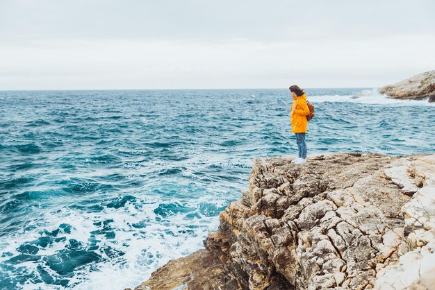 Femme debout sur la falaise regardant la mer