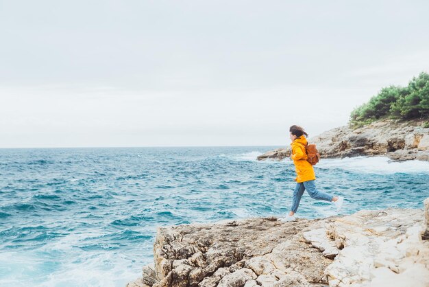 Femme debout sur la falaise regardant les tempêtes d'été en mer