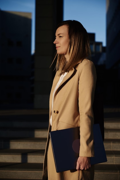 Femme debout sur les marches à l'extérieur avec un ordinateur portable